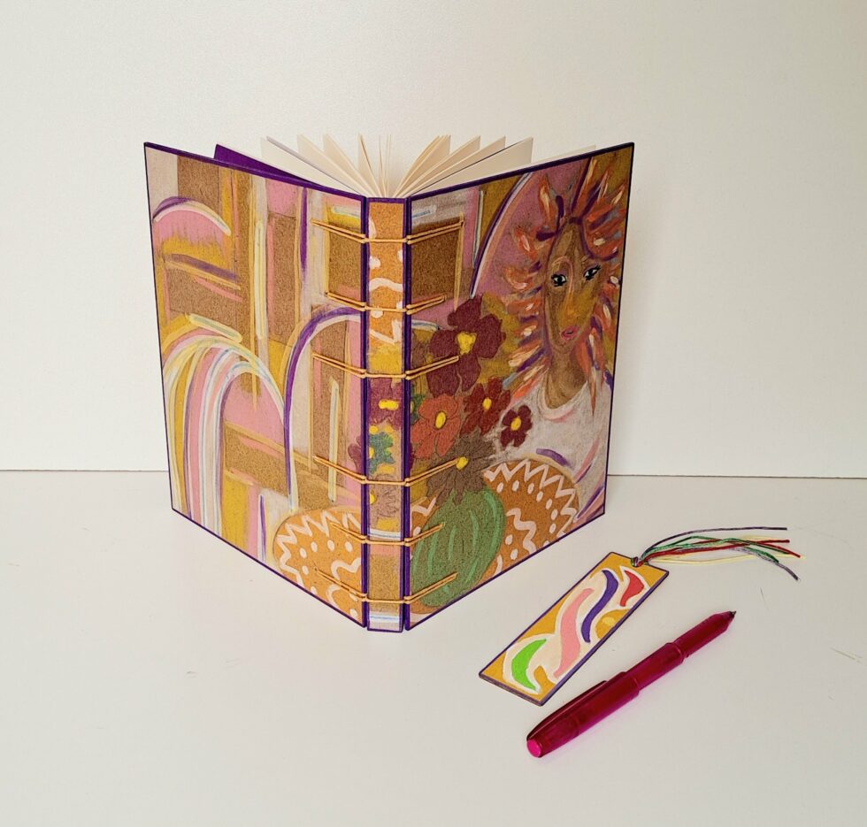 Carnet SUZANA ouvert avec un stylo rose et un marque-page en bois