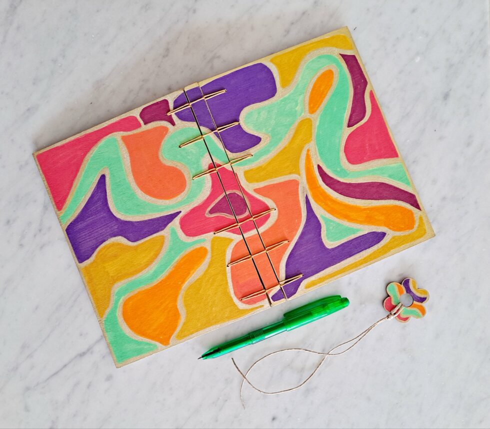 Carnet NÄSS couverture ouverte avec stylo et marque page en bois.