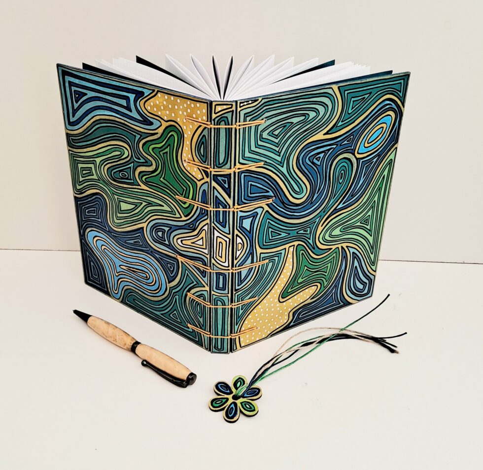 Carnet HOULE vue ouvert debout avec stylo en bois et marque page fleur.