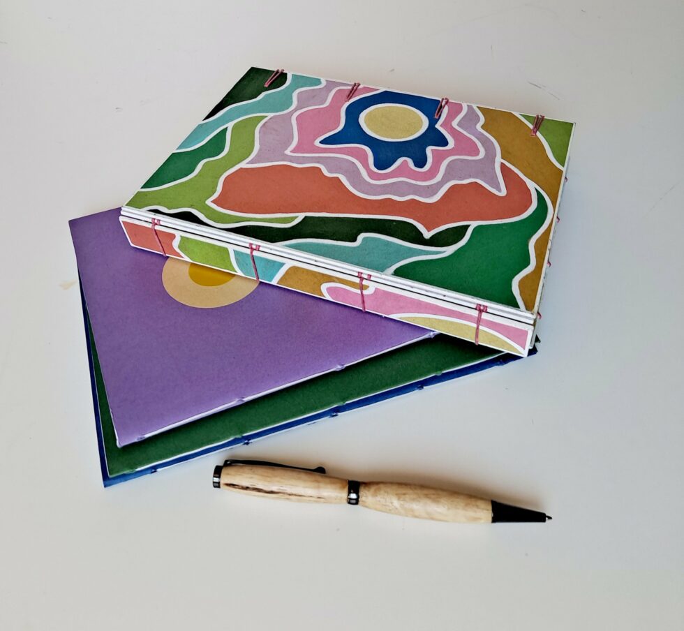 Boîte à mots CHARLIE vue recto à plat sur dos avec carnets et stylo en bois.
