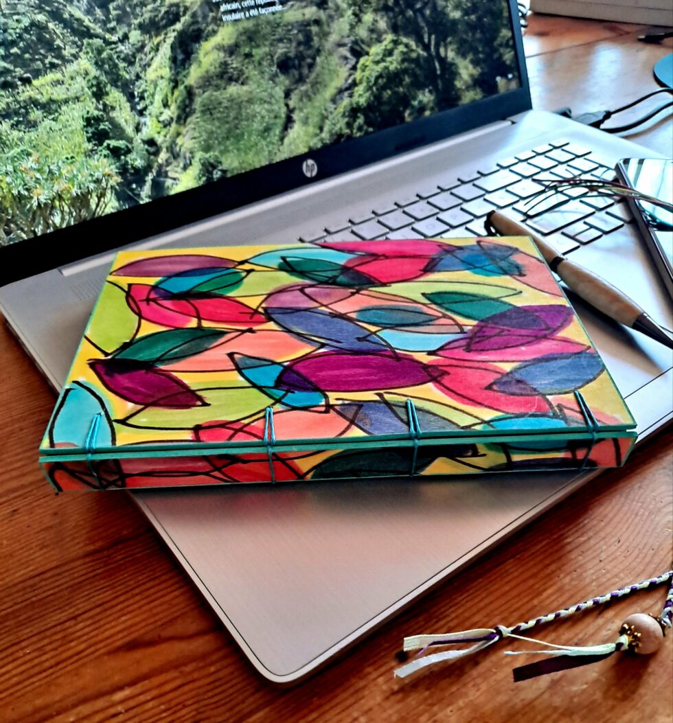 Carnet JELLY vue recto à plat avec stylo en bois, marque-pages et ordinateur.