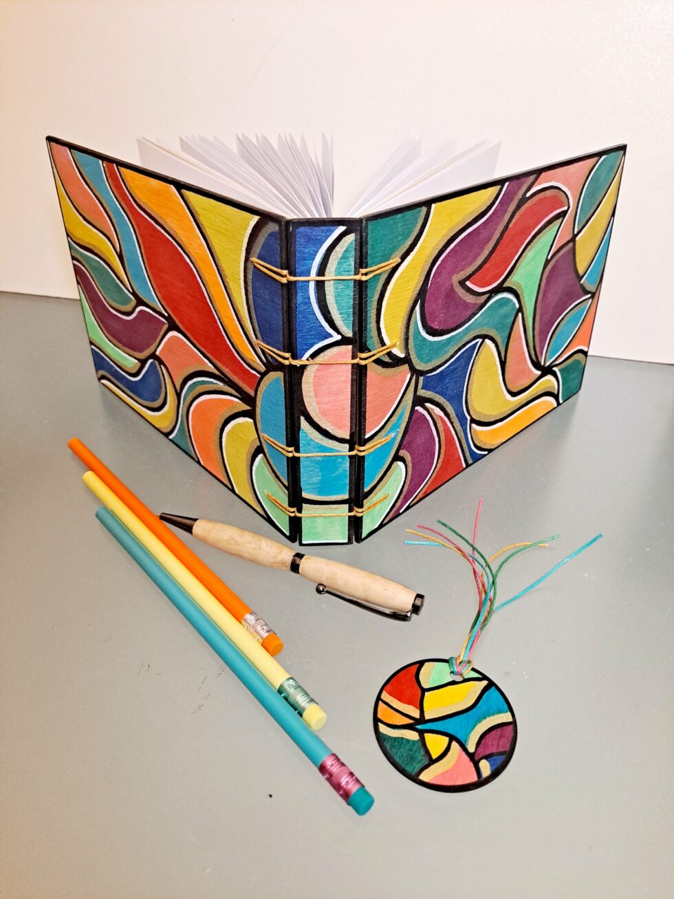 Album DISCO vue recto verso debout avec stylo en bois et marque pages en bois peint.