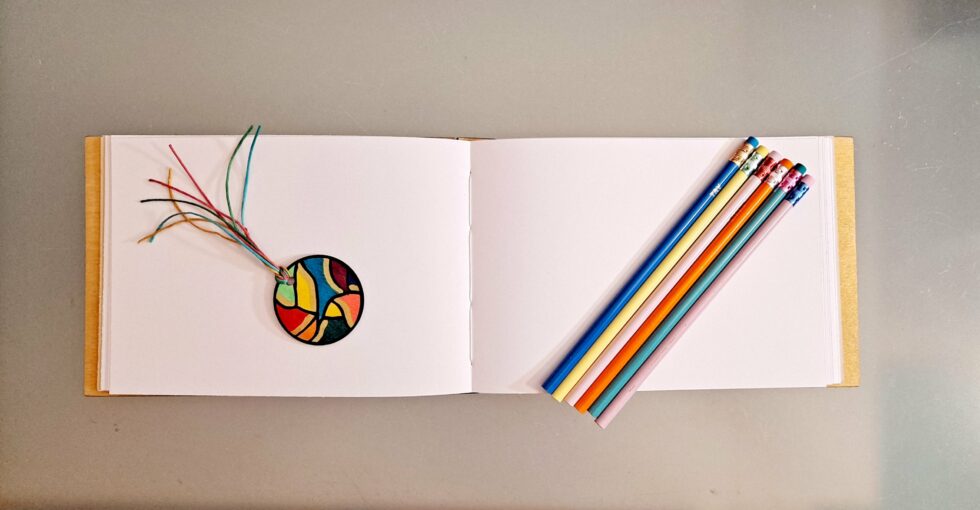 Carnet DISCO vue intérieure sur pages et crayons de couleurs avec gomme et marque-pages en bois peint.