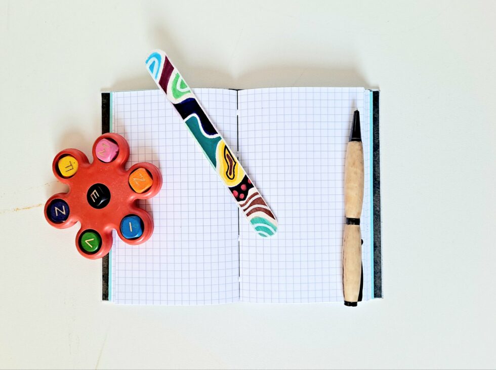 Carnet ATOCA vue recto verso sur pages avec stylo en bois et marque pages en bois peint.