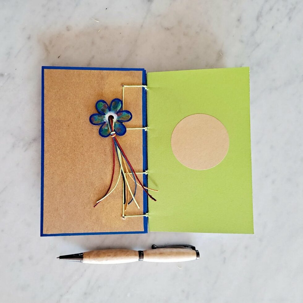 Carnet GENTIANE vue intérieure sur couverture avec reliure fil jaune et marque-pages fleur et stylo en bois.