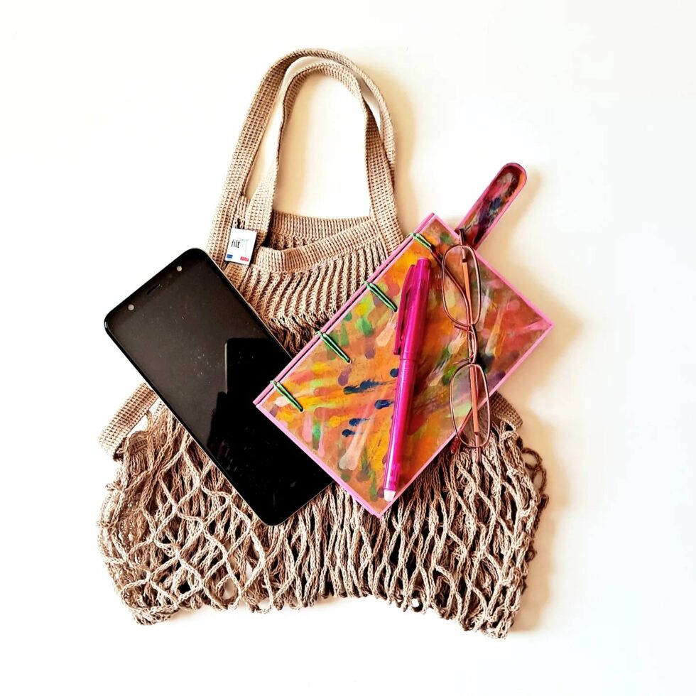 Carnet MONA, vue sur sac avec marque-pages en bois et stylo rose.