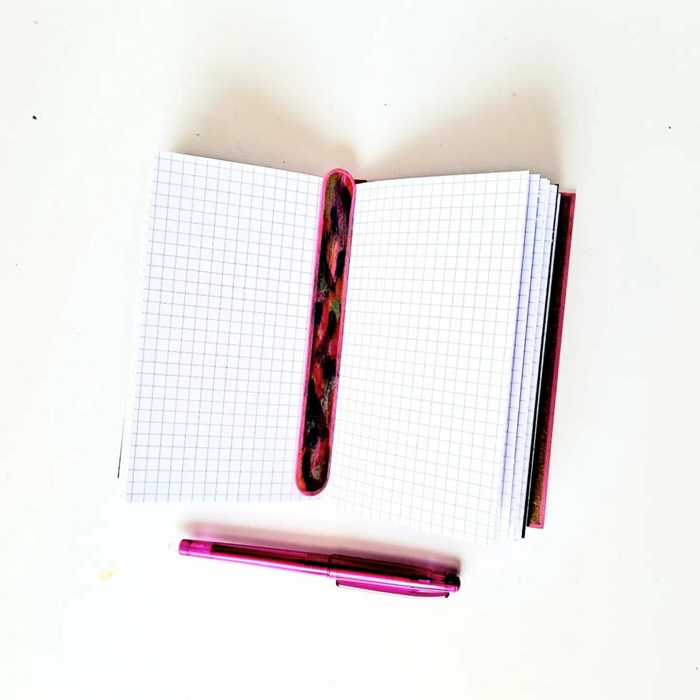 Carnet MONA, vue intérieure sur pages avec marque-pages en bois et stylo rose.