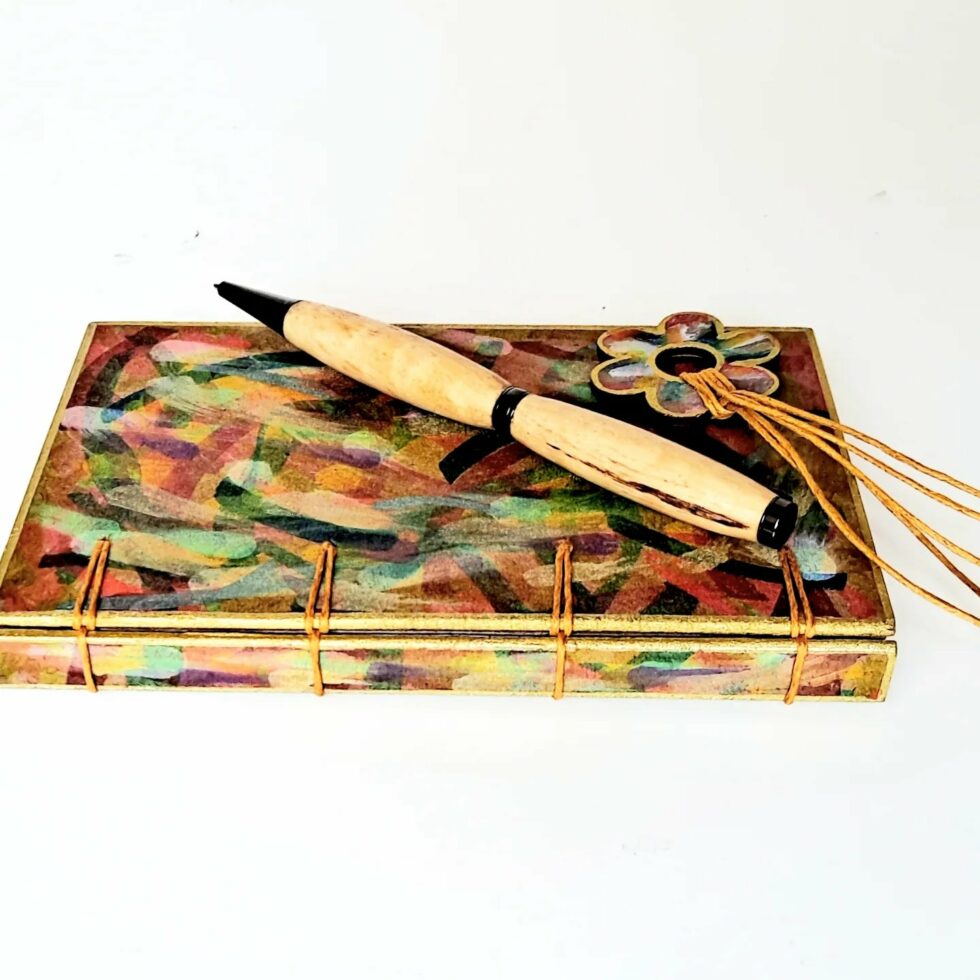 Carnet FIDJI vue recto sur reliure dos avec marque-pages fleur et stylo en bois.
