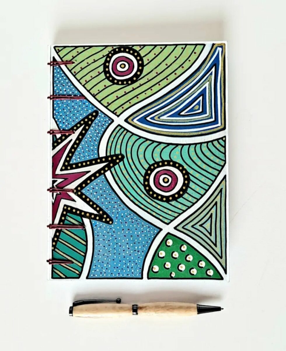 Carnet DJINJA, vue recto avec stylo en bois et reliure rouge.