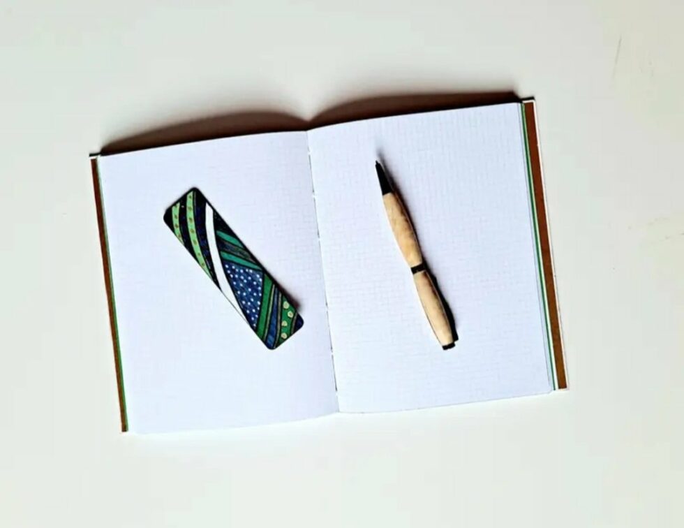 Carnet DJINJA, vue intérieure sur pages avec stylo en bois et reliure rouge.