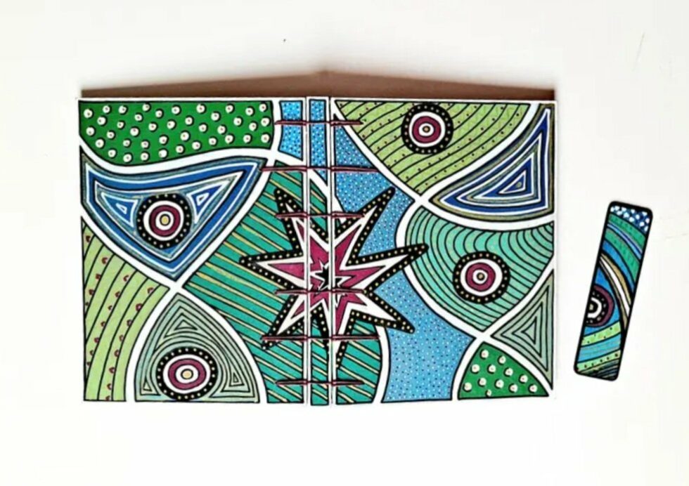 Carnet DJINJA, vue recto verso à plat avec stylo en bois et reliure rouge.