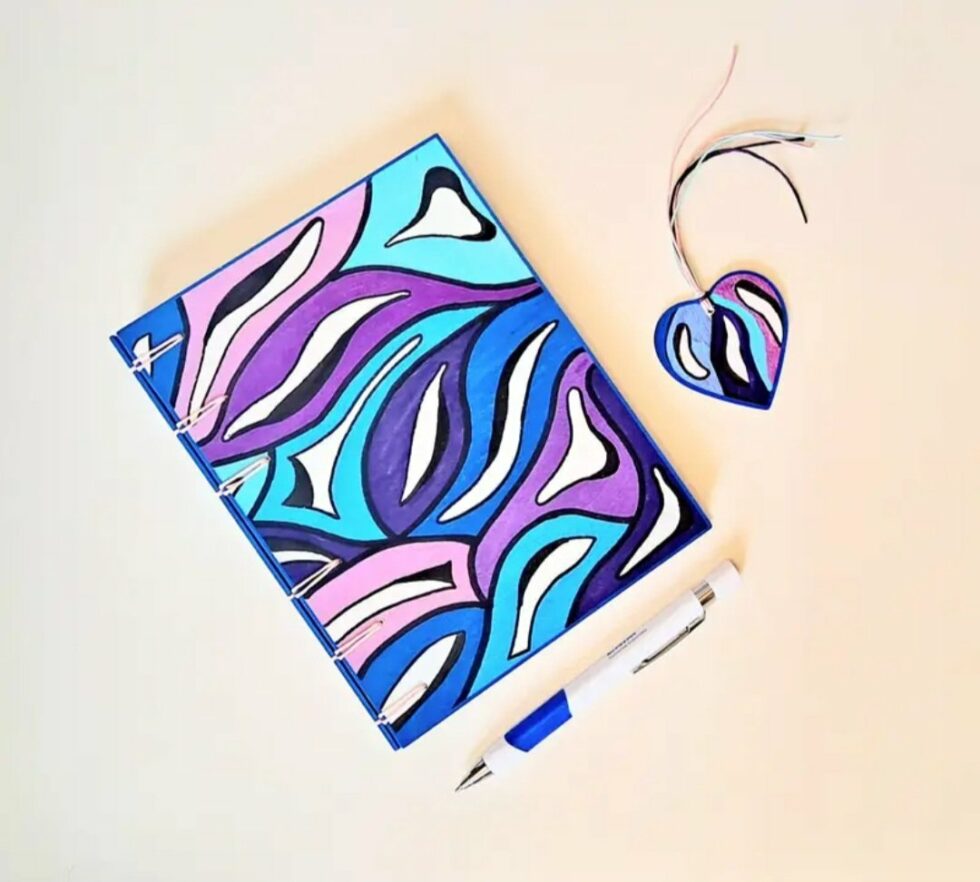 Agenda KISS vue recto à plat avec marque-pages cœur en bois peint et stylo bleu et blanc..