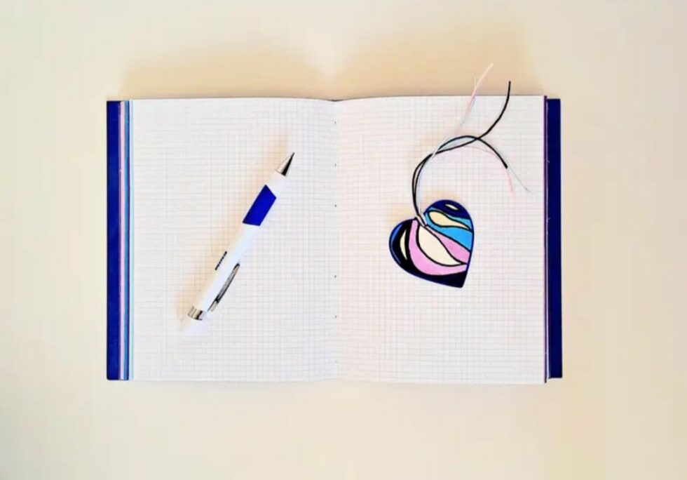 Agenda KISS vue intérieure sur pages avec marque-pages cœur en bois peint et stylo bleu et blanc..