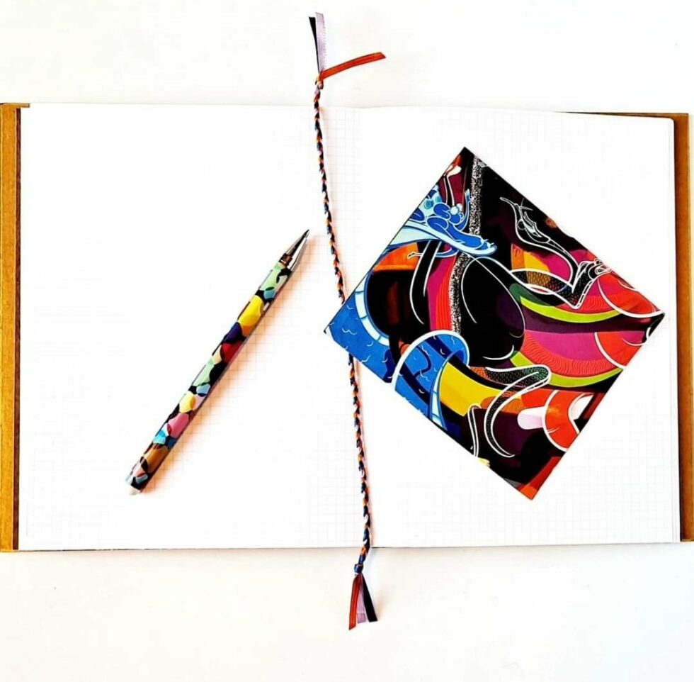 Carnet FARRAGO, vue recto verso intérieur à plat avec dos avec reliure turquoise et stylo multicolore.
