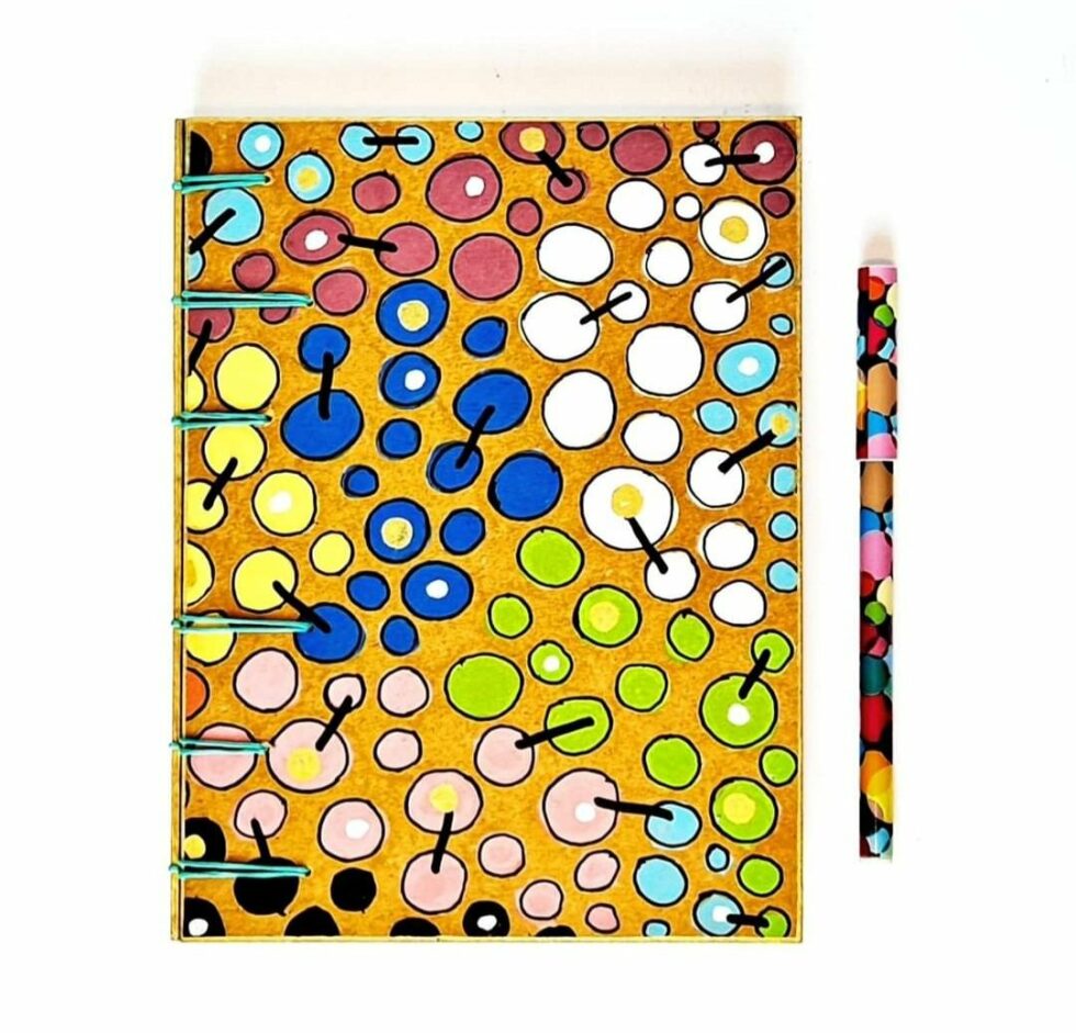 Carnet FARRAGO, vue recto avec reliure turquoise et stylo multicolore.