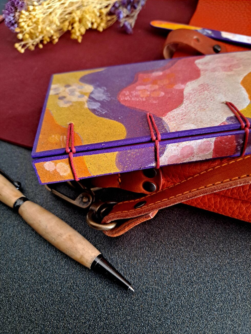 Carnet PASTORAL vue dos et reliure rouge avec stylo en bois et marque page en bois peint.