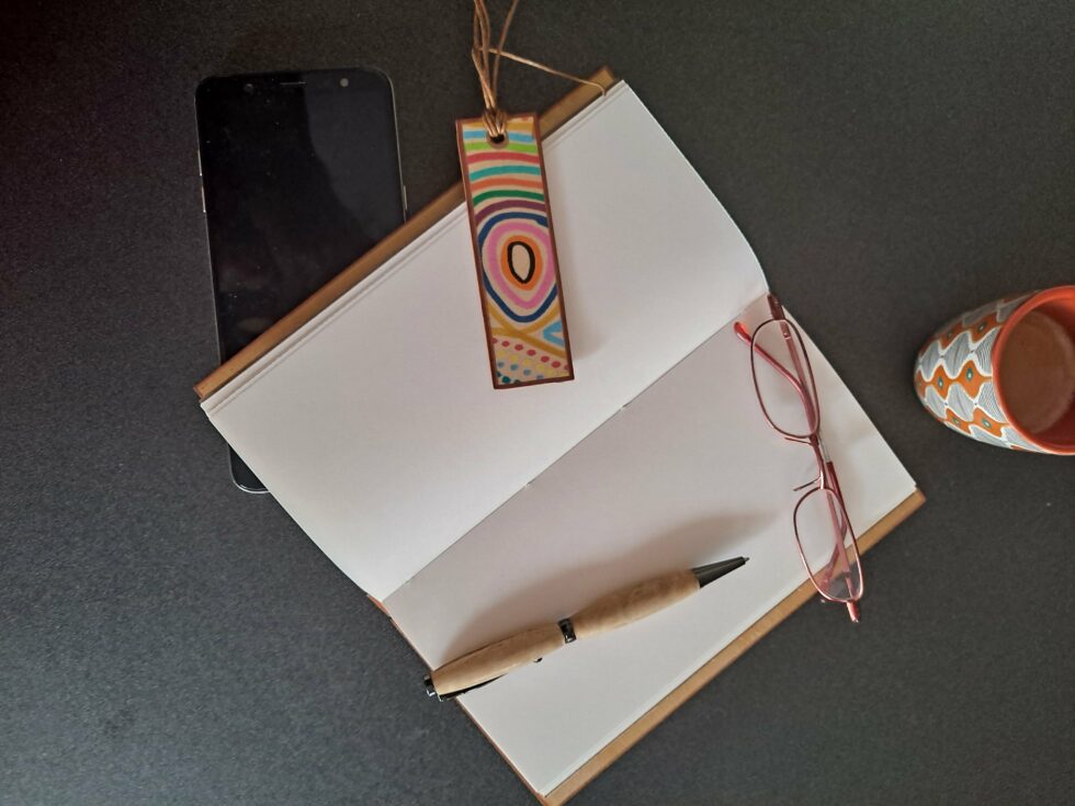 Carnet KIMBA, vue recto verso sur pages avec marque-pages en bois peint à la main et stylo et tasse à café.