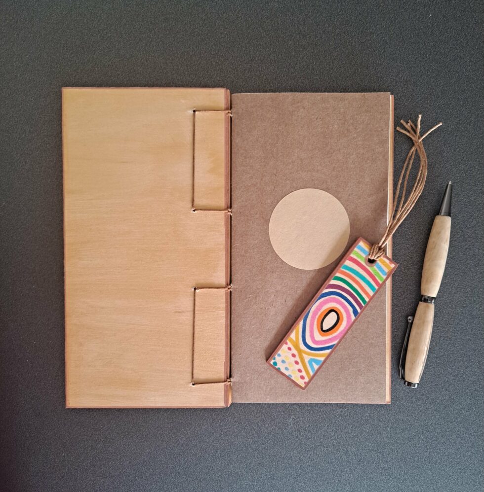 Carnet KIMBA, vue recto verso sur page de garde avec marque-pages en bois peint à la main et stylo en bois.