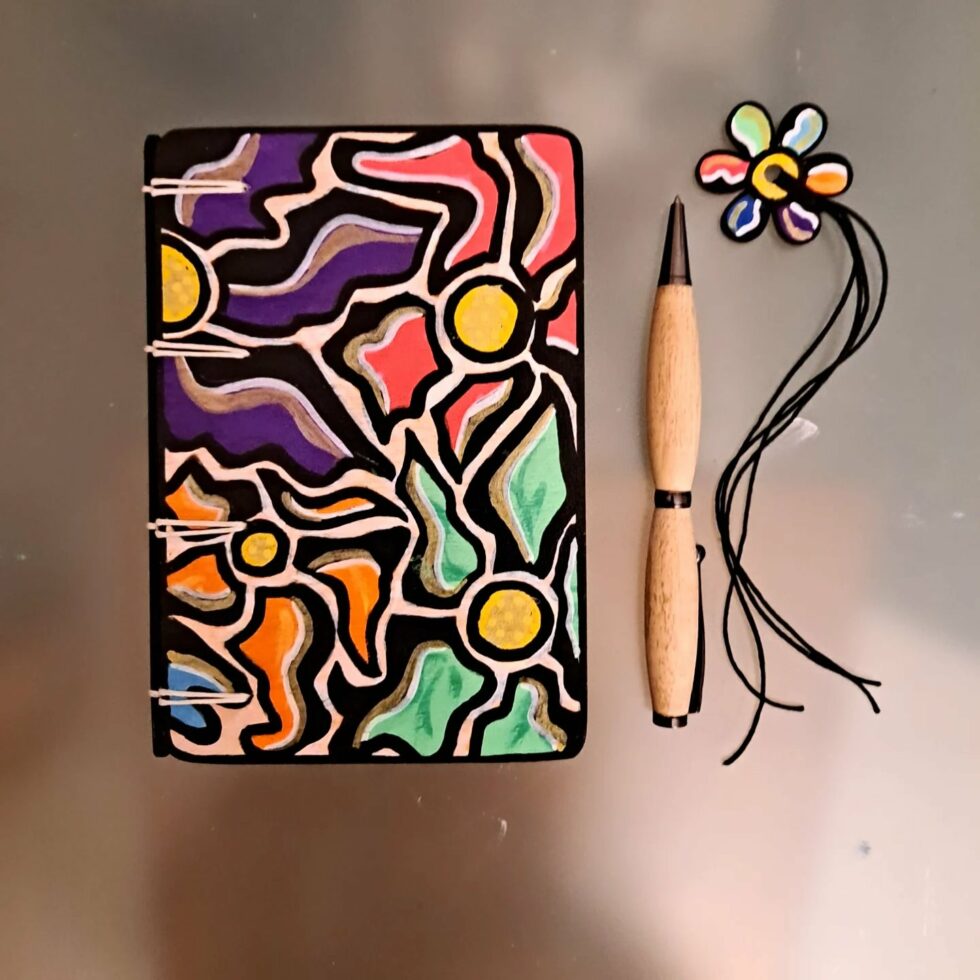 Carnet FLEUR, vue recto sur couverture en bois peint avec marque-pages en bois peint et stylo. avec marque-pages en bois peint et stylo. avec marque-pages en bois peint et stylo.