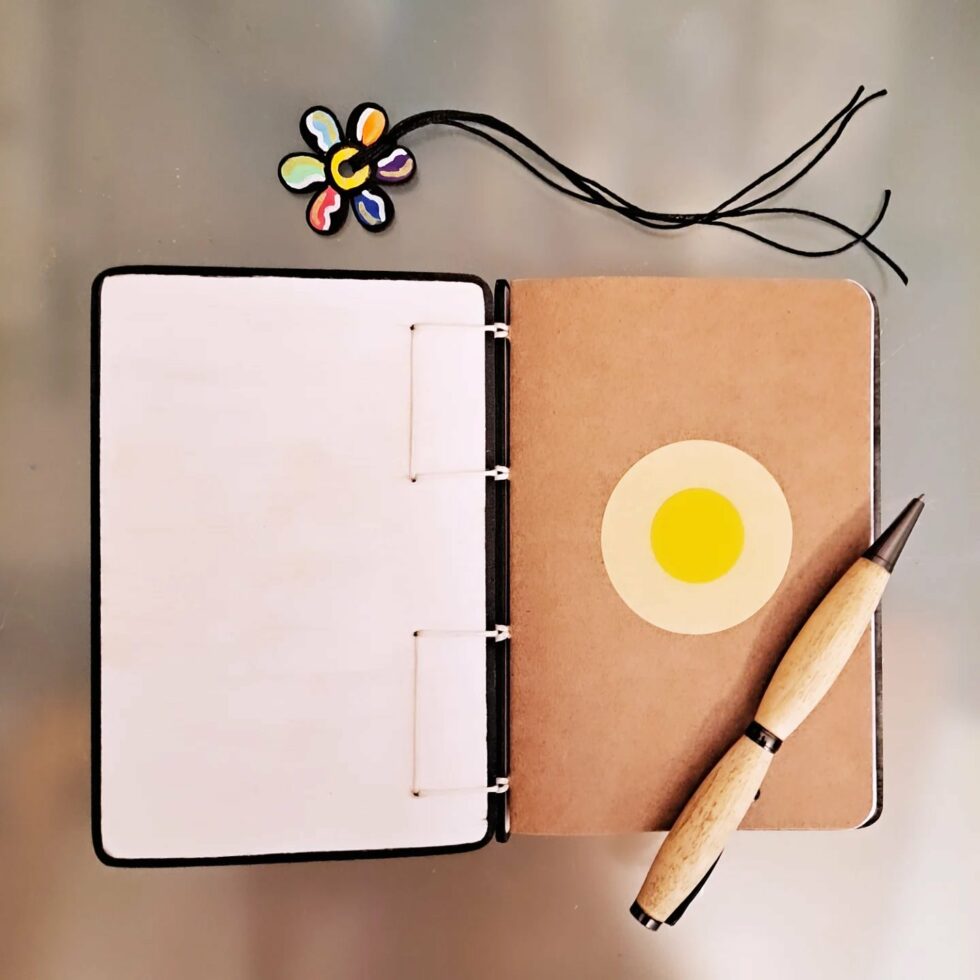 Carnet FLEUR, vue intérieur sur couverture et page avec marque-pages en bois peint et stylo.
