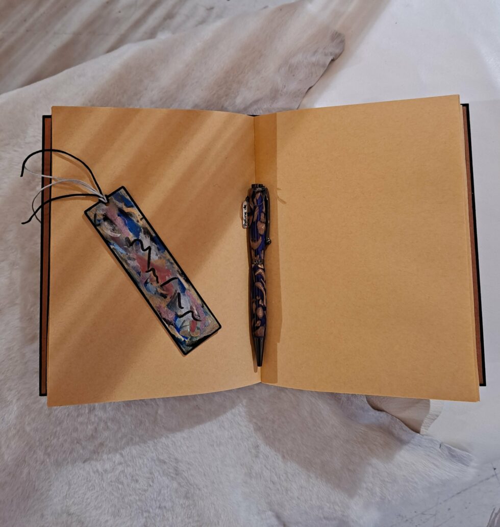 Carnet FRAC, vue intérieure sur pages kraft avec marque-pages en bois peint et stylo.