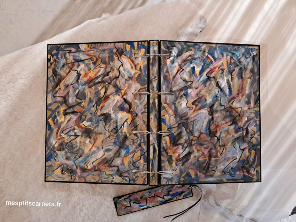 Carnet FRAC, vue recto verso à plat avec marque-pages en bois peint et stylo.