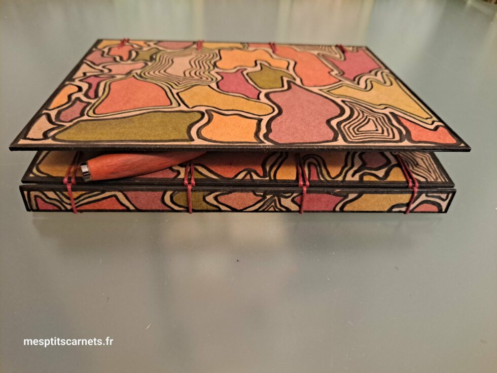 Carnet Triptyque SILICE vue semi ouvert à plat avec dos et couverture en bois peint et stylo.