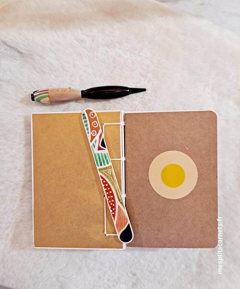Carnet PHARE, vue intérieur sur pages à plat et couverture avec marque-pages en bois peint et stylo.