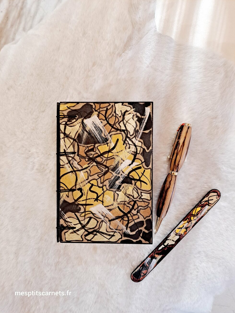 Carnet GREG, vue recto à plat et couverture avec marque-pages en bois peint et stylo.
