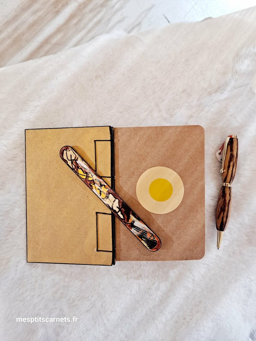 Carnet GREG, vue intérieur pages à plat et page de garde couverture avec marque-pages en bois peint et stylo.